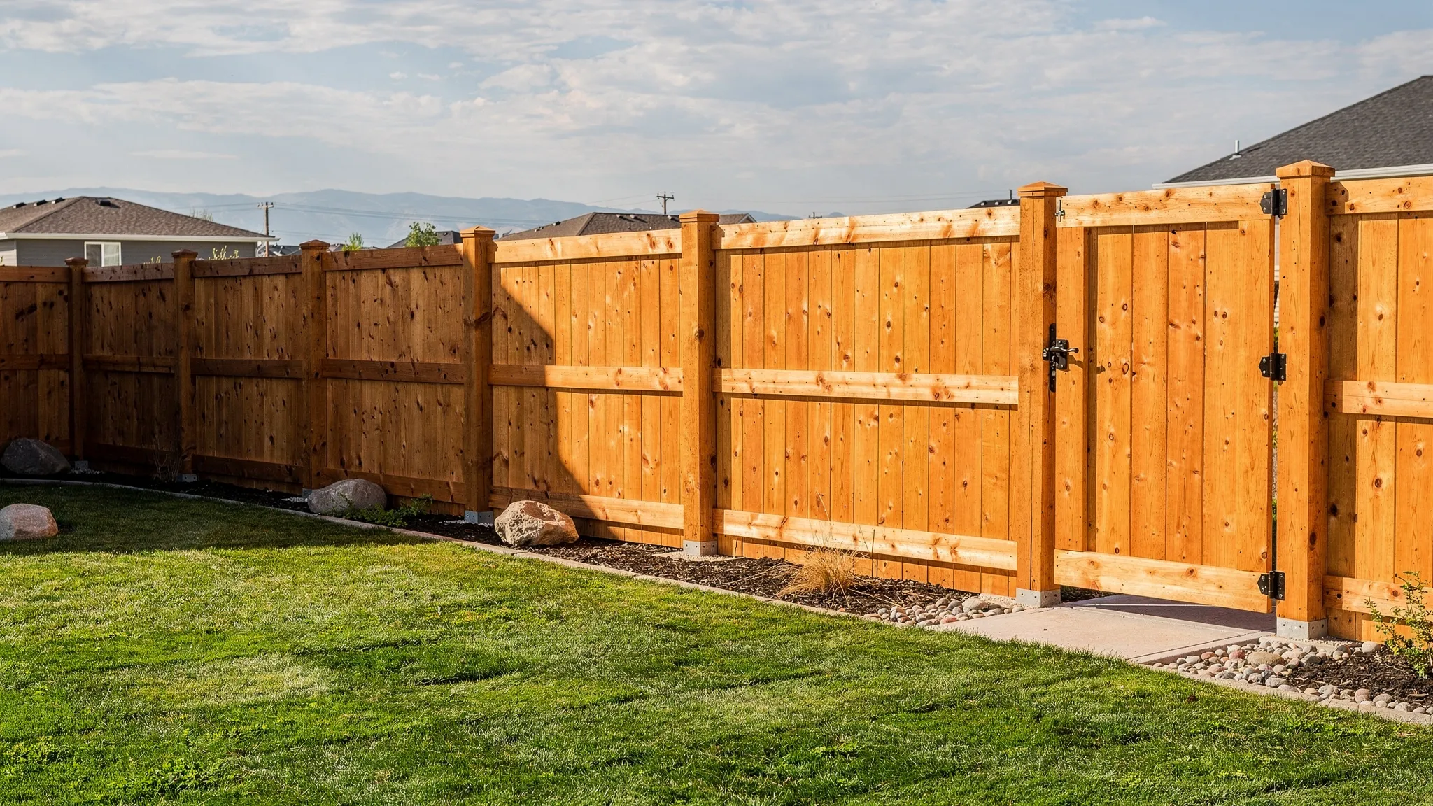 A newly installed cedar-style wood privacy fence around a clean backyard in Twin Falls, with sturdy posts, straight fence lines, a walk gate, and open Idaho sky in the background.